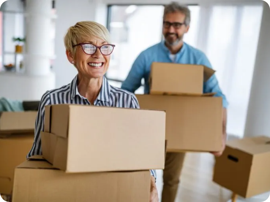 Two smiling people hold boxes.