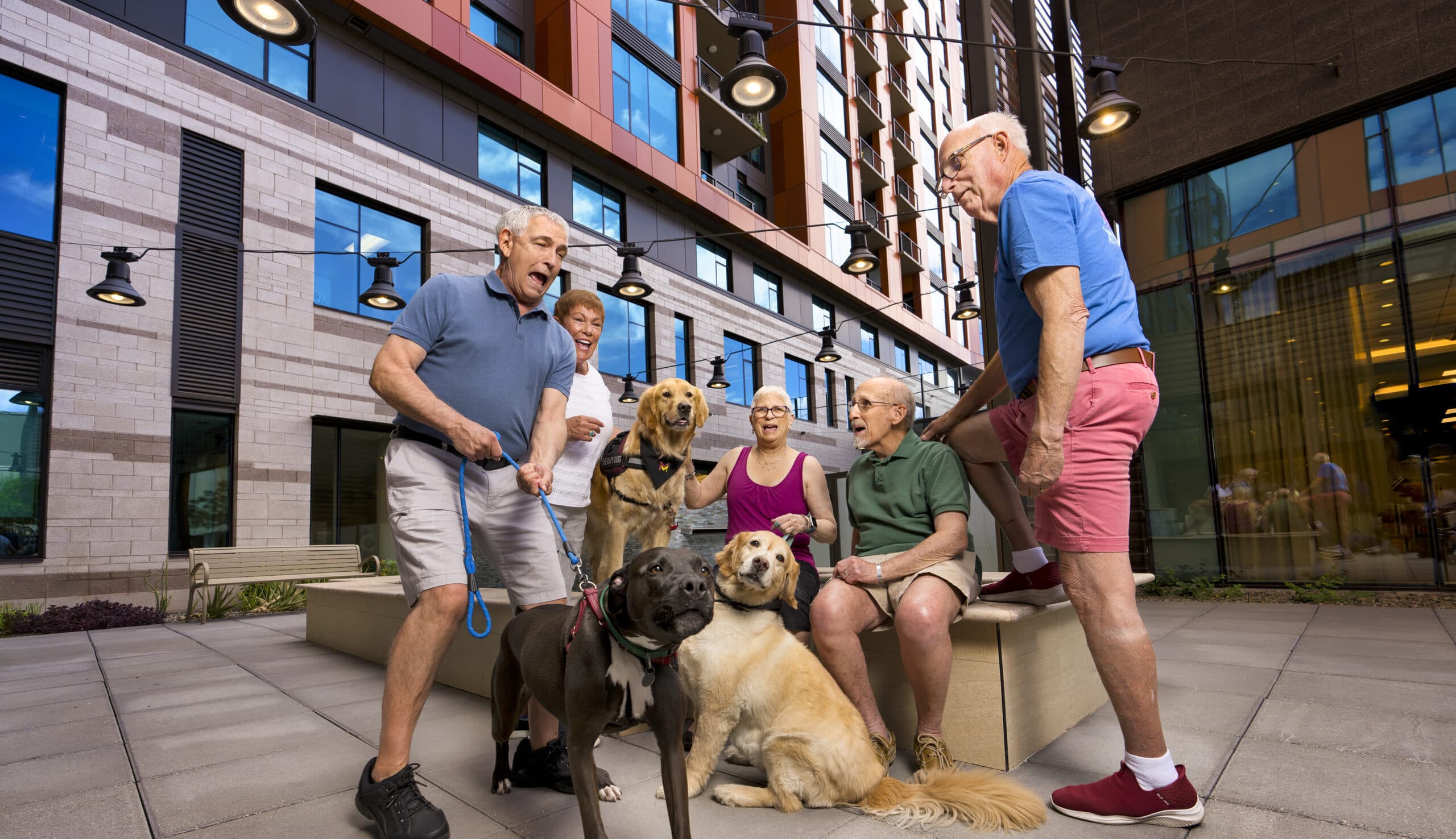 A group of cheerful residents and dogs outdoors.